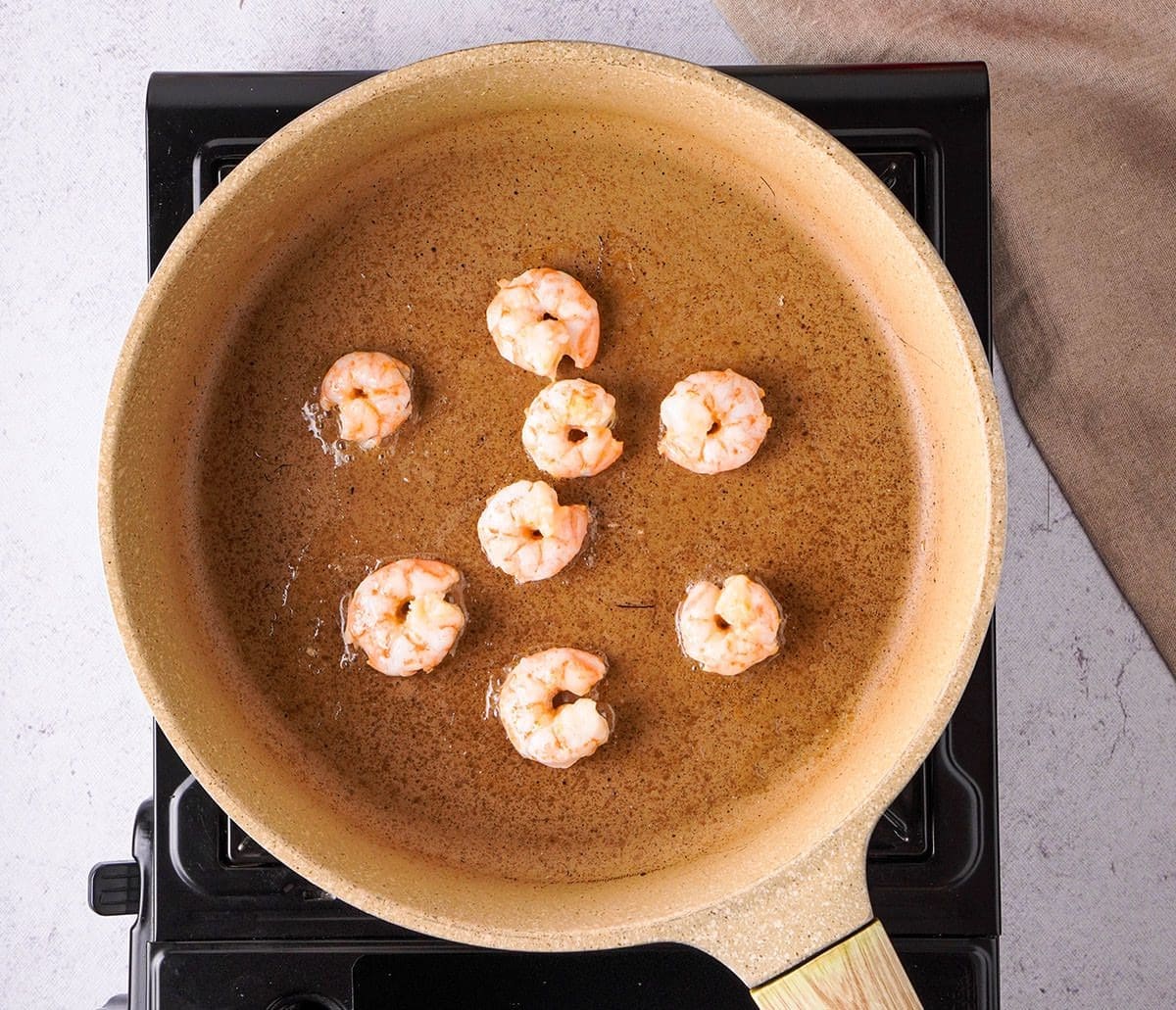 Shrimp cook in a pan full of oil.