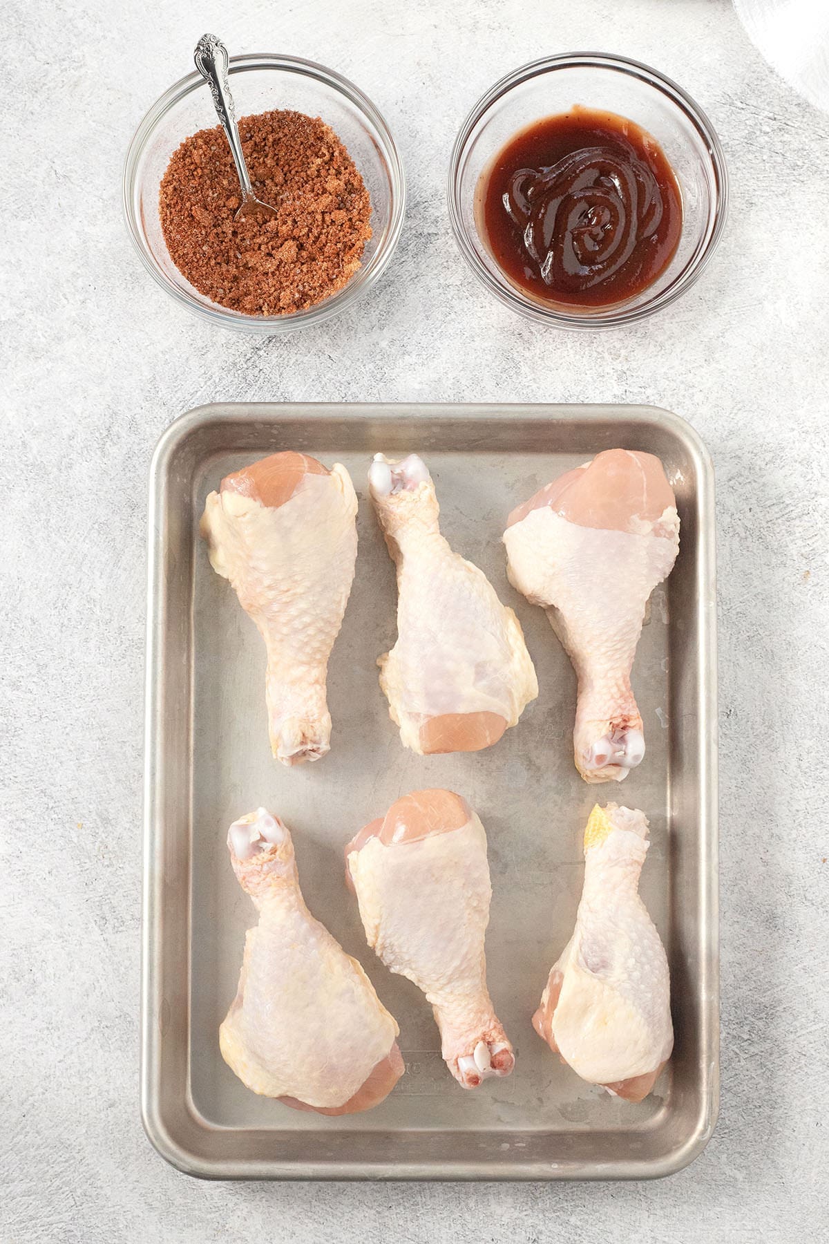 Raw poultry legs on a baking sheet.