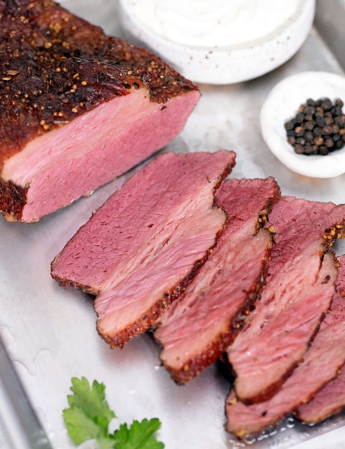 Sliced meat on a silver baking sheet.