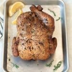 Smoked whole chicken on a silver baking sheet.