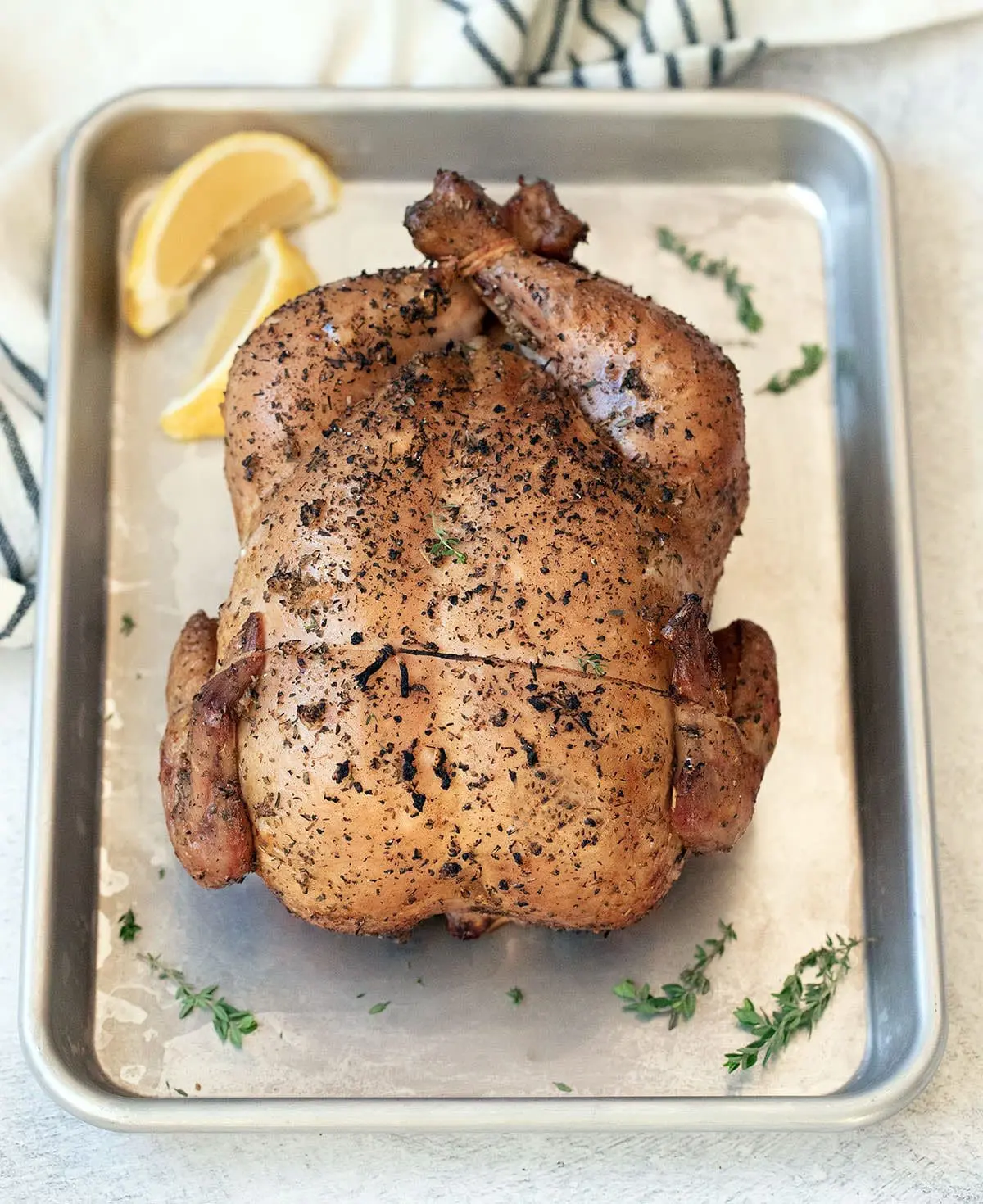 Smoked whole chicken on a silver baking sheet.