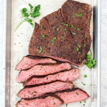 Slices of sous vide london broil on a silver baking sheet.