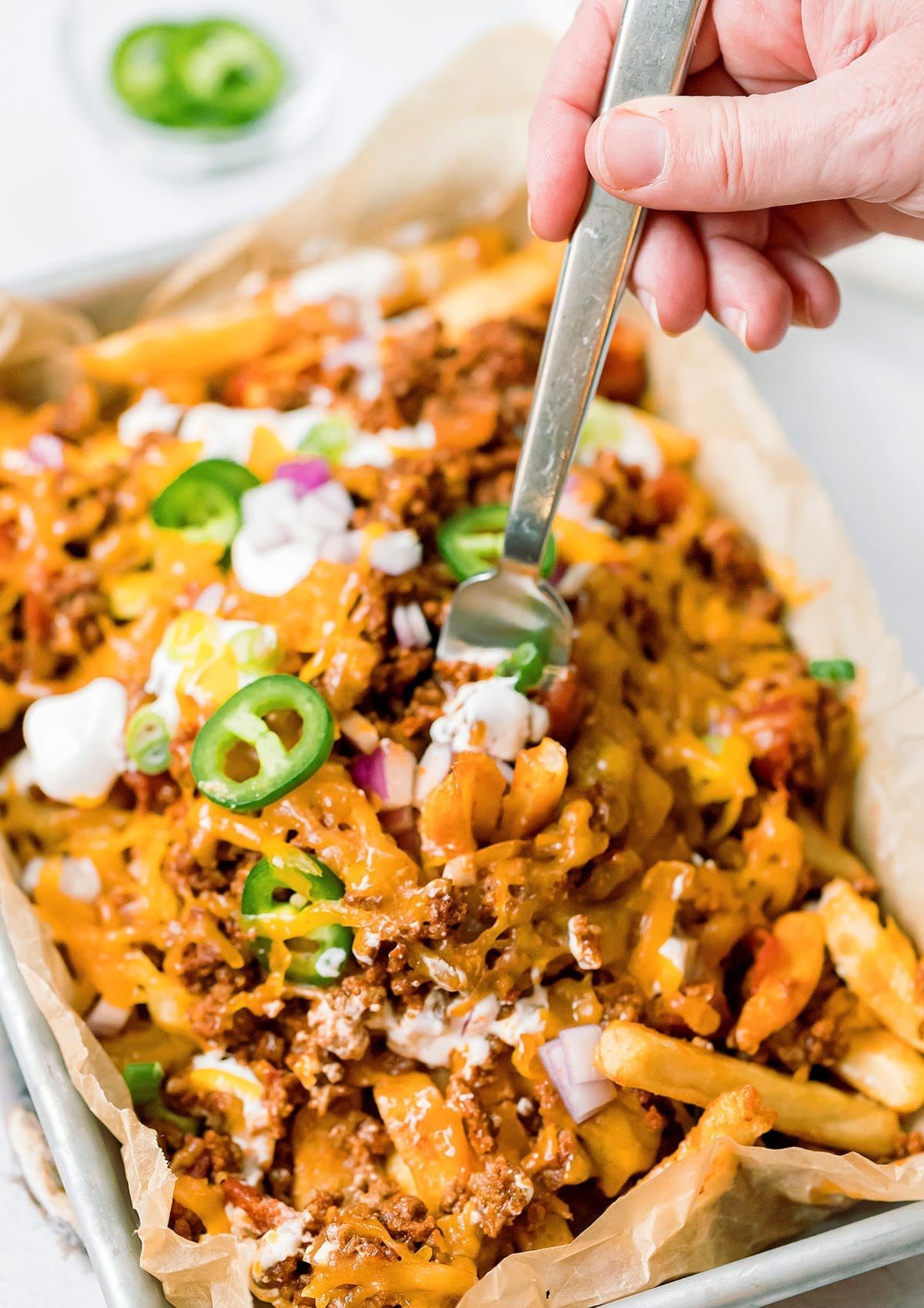 Fork digging into a tray of chili cheese fries.