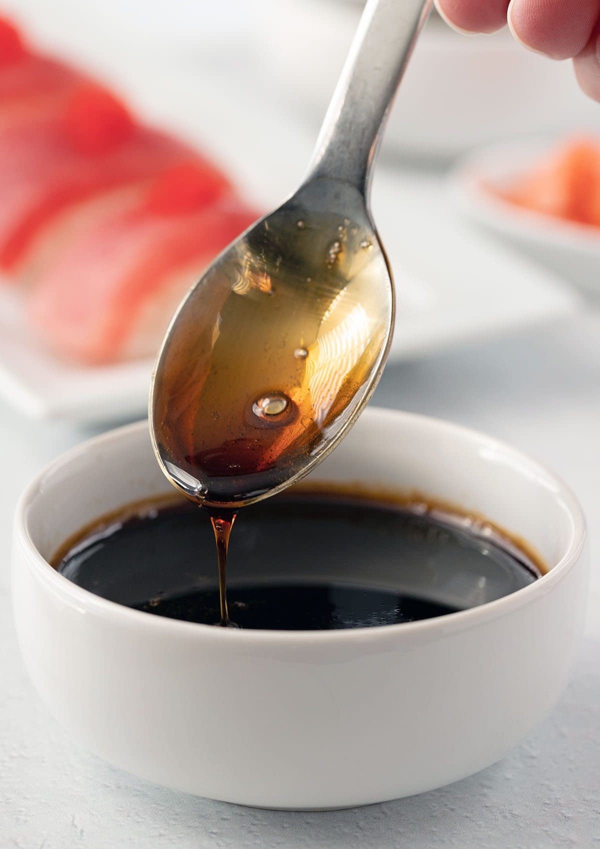 Eel sauce in a white bowl with a silver spoon.