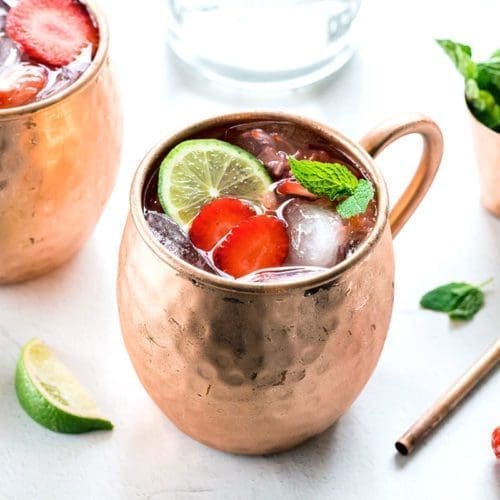 Three copper mugs full of strawberry mules garnished with mint leaves.