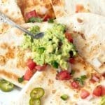 Sliced cheese quesadilla topped with quacamole.