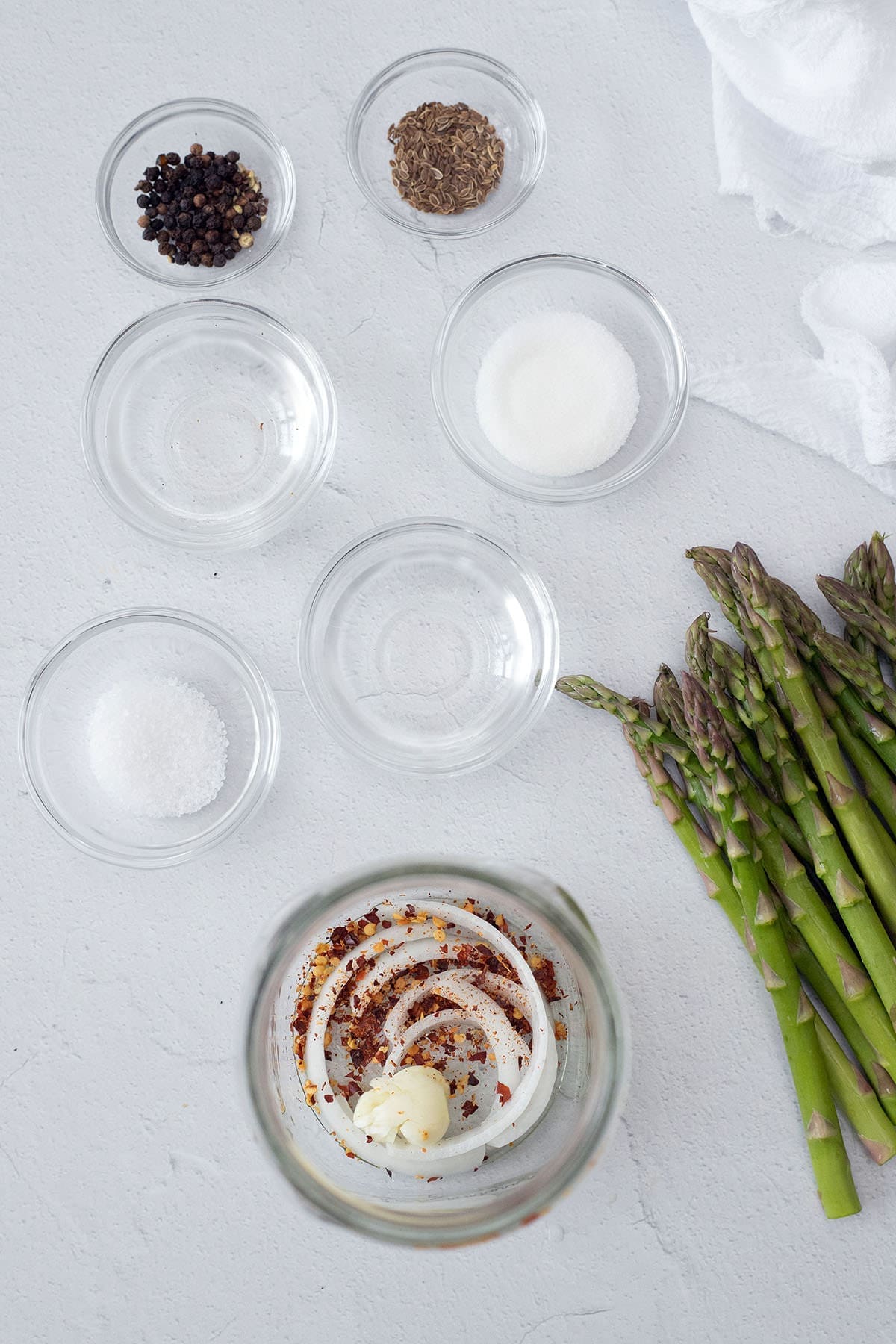 Glass bowls with spices next to stalks of asparagus.