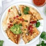 steak quesadilla with guacamole and pico de gallo on top.