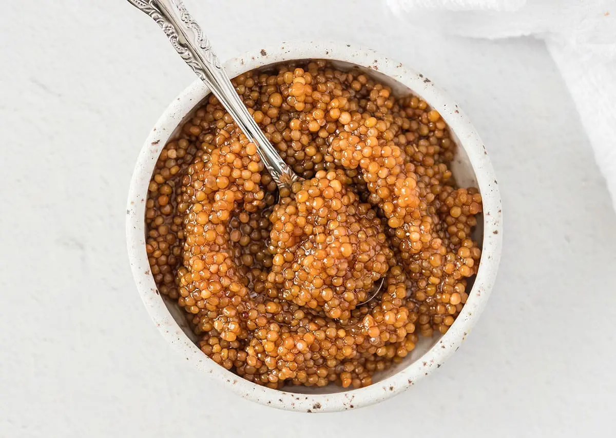 Pickled Mustard seeds in a small bowl with a silver spoon.