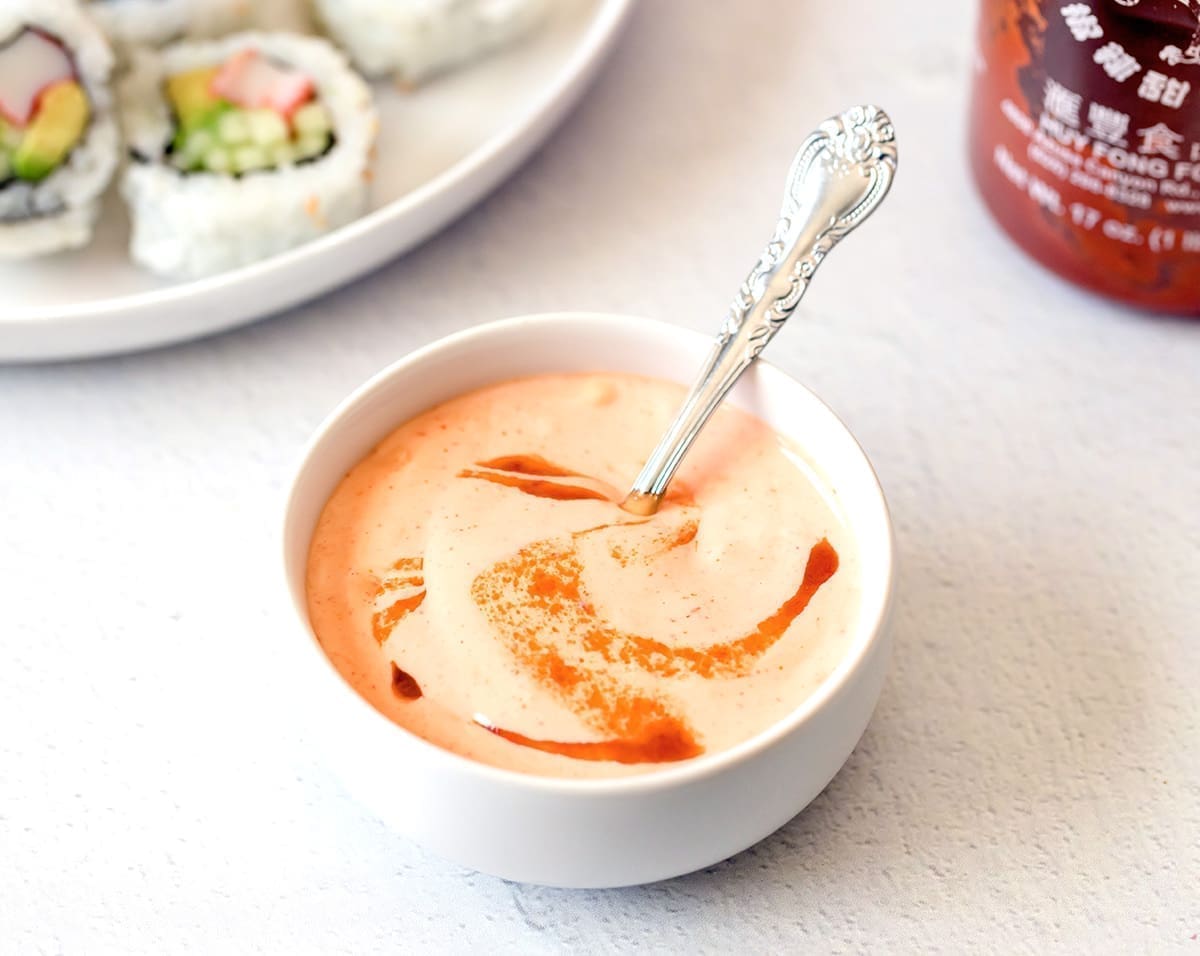 Sriracha aioli in a small white bowl with a spoon.