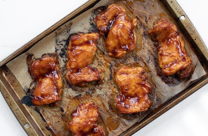 Baked BBQ Chicken Thighs on a cooking sheet.
