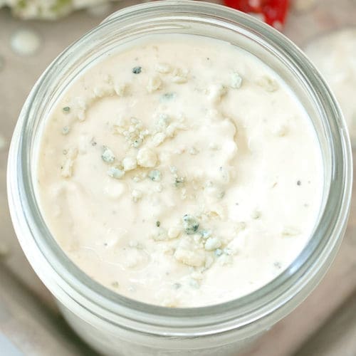 Blue cheese sauce in a clear glass jar.