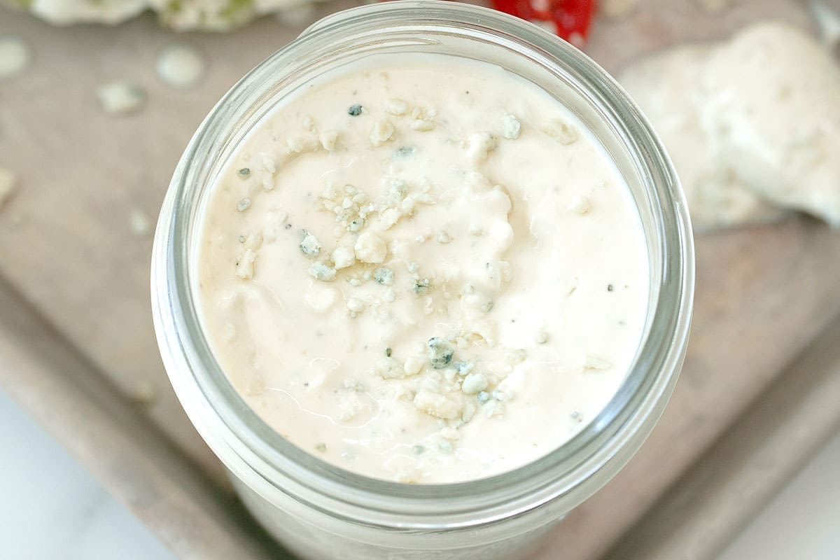 Blue cheese sauce in a clear glass jar.