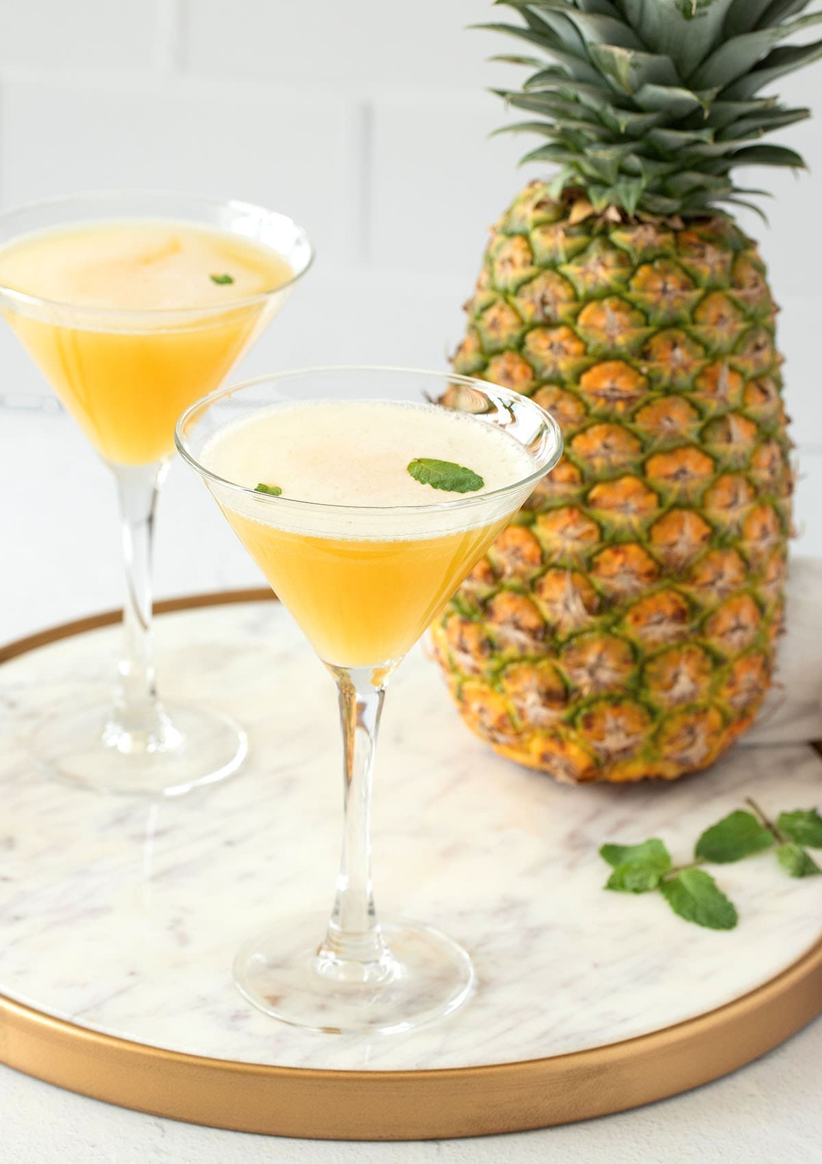 Two pineapple martinis next to a fresh pineapple