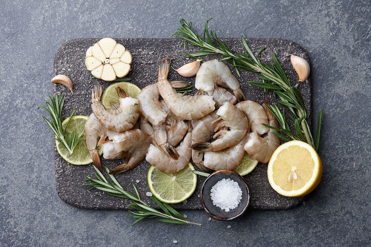 Various shrimp sizes on a black cutting board.