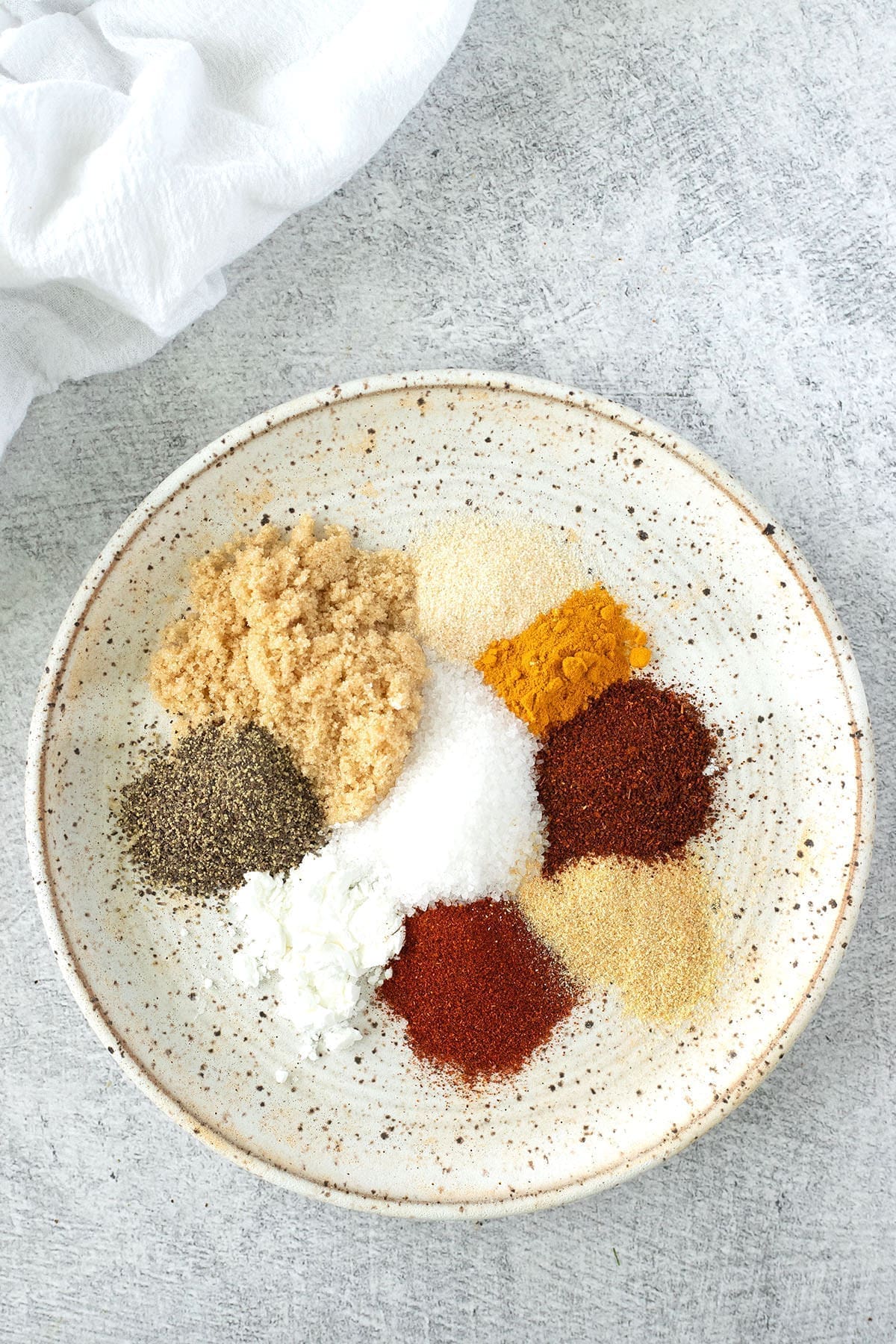 Variety of different spices spread out on a deckled plate.