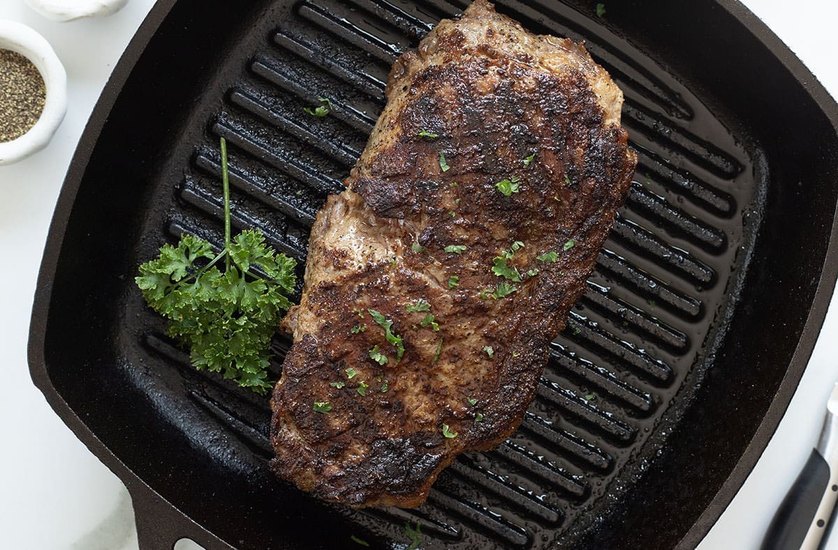 New York Strip Steak on a black griddle.