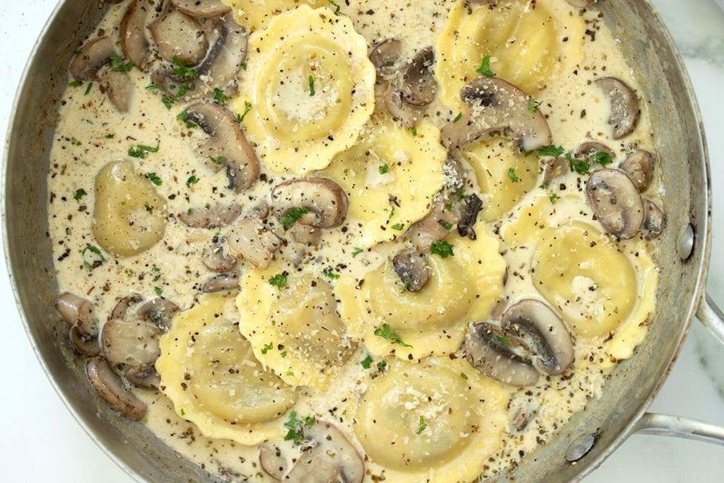 Mushroom ravioli in a silver frying pan.