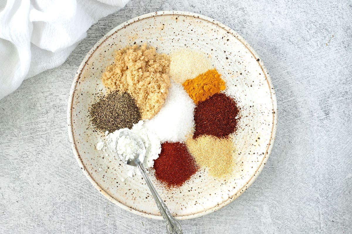 Variety of different spices spread out on a deckled plate.
