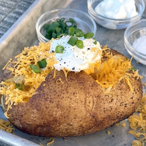 Smoked baked potato topped with cheese and sour cream.