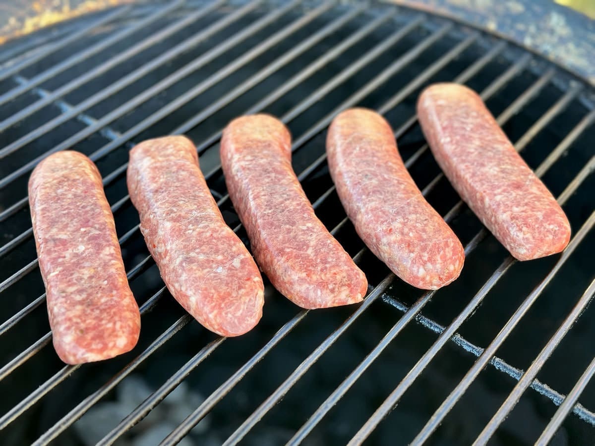 Uncooked sausage links on a grill.