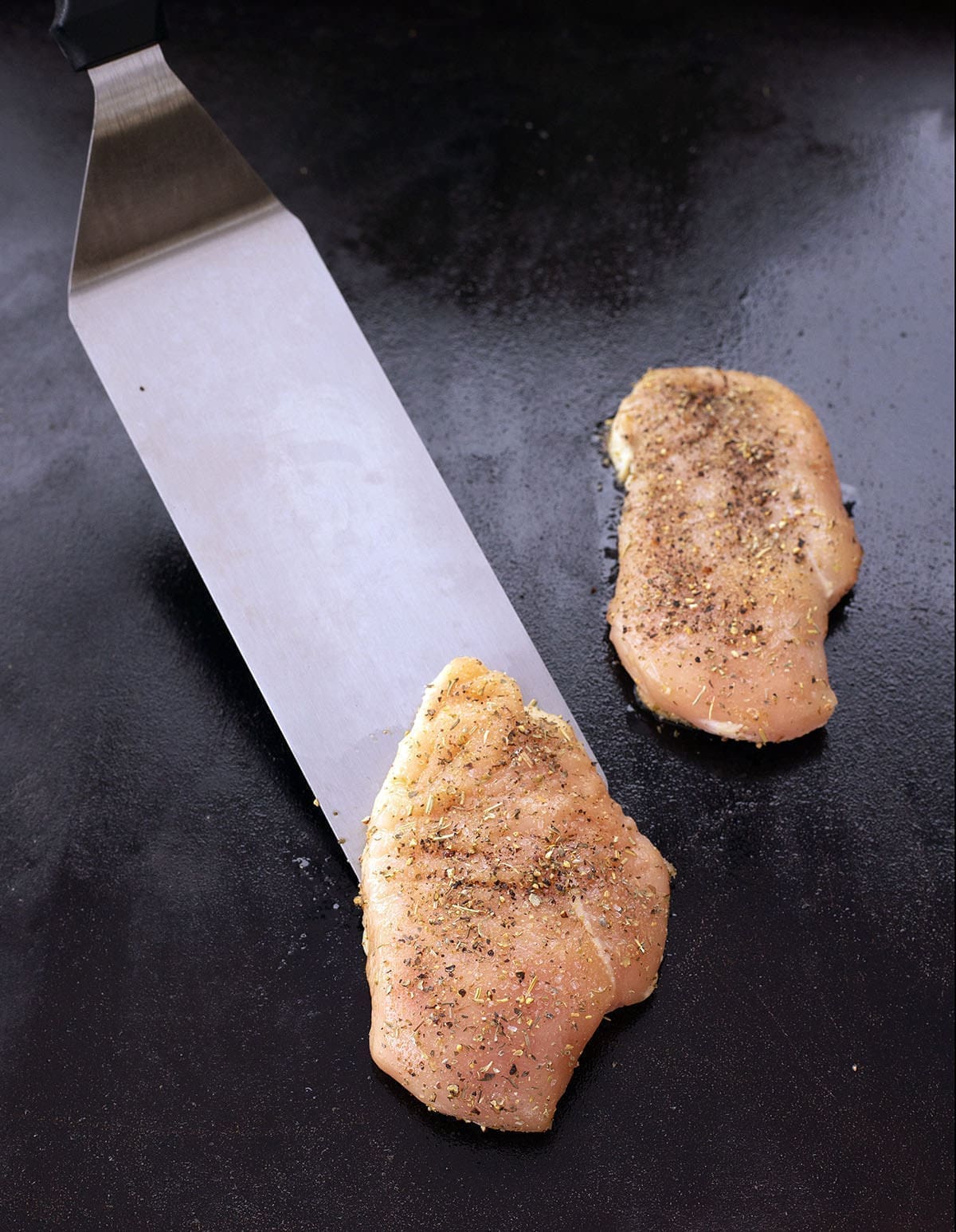 chicken breasts on a blackstone being flipped.