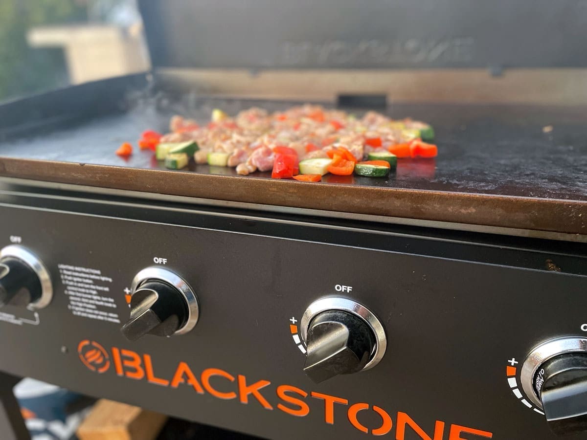 chicken and vegetables grilling on a blackstone.