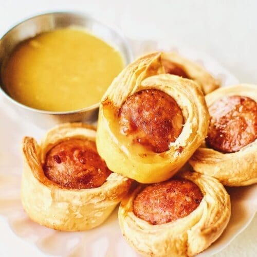 Sausage wrapped in puff pastry by mustard dipping sauce.