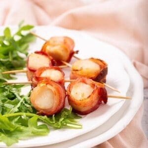 bacon wrapped scallops garnished with arugula.