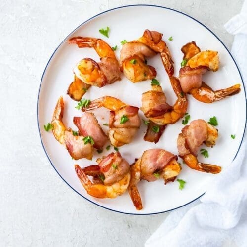Bacon wrapped shrimp on a white plate.