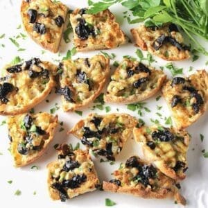 Cheese and olive appetizer bites on a white plate.