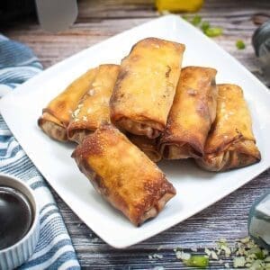 Philly cheesesteak egg rolls on a white plate.