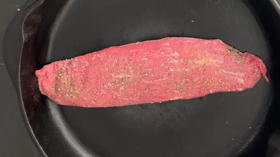 Seasoned beef steak in a cast iron pan.