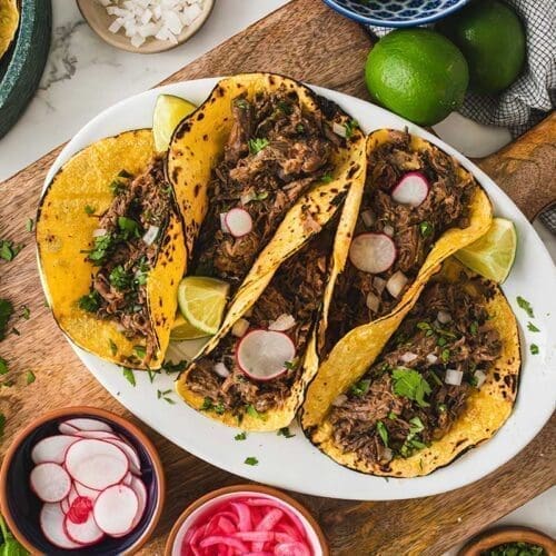 30+ Beef Chuck Roast Recipes 12 Barbacoa tacos on a white serving dish.