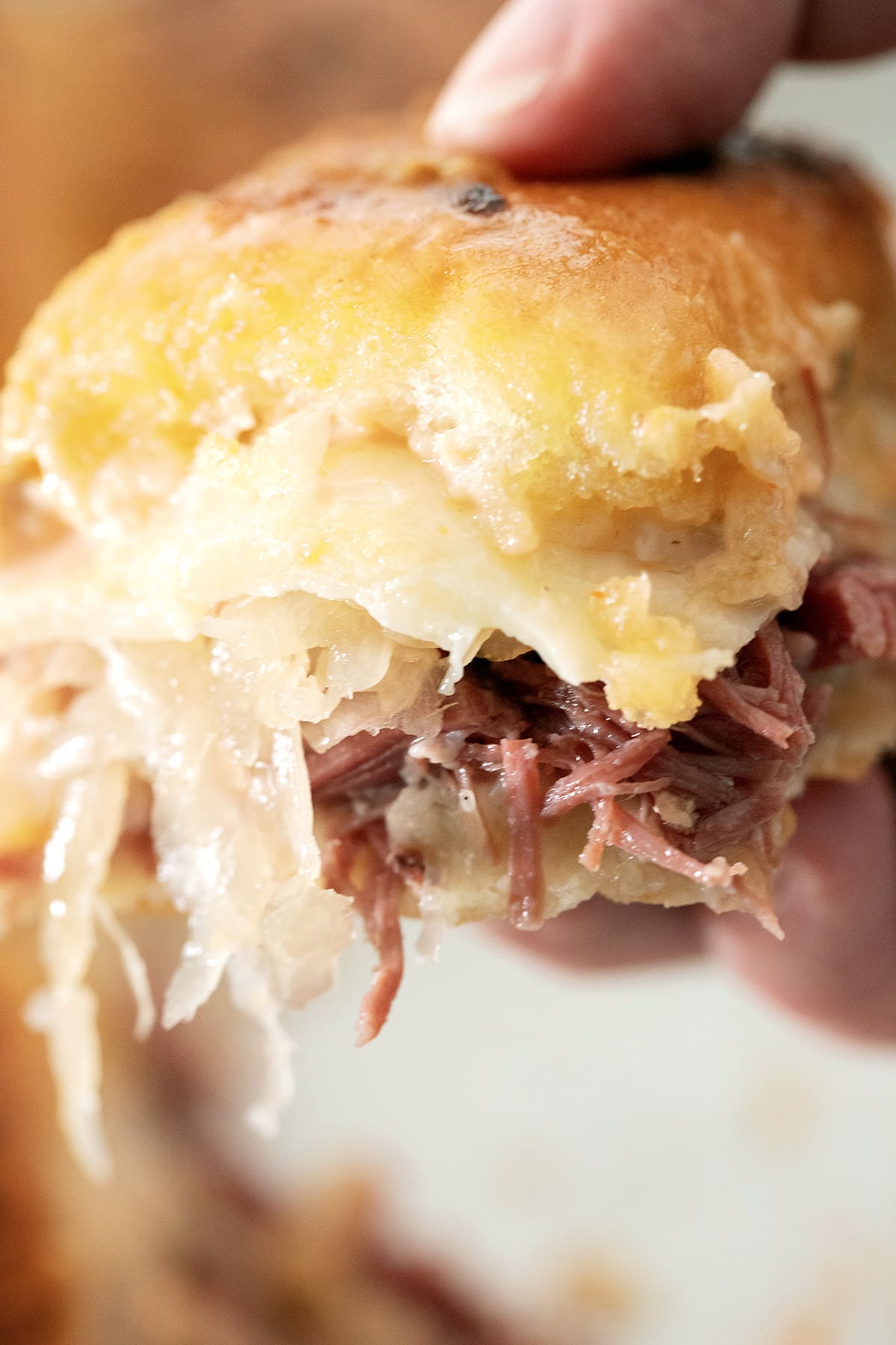 Hand holding up one Corned Beef Slider.