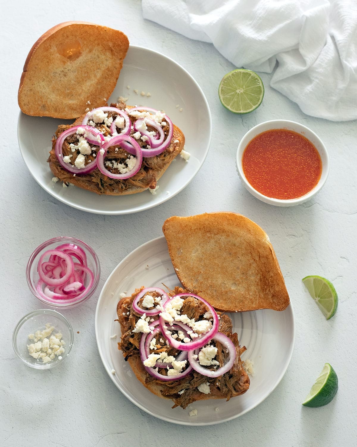 Two open faced Torta Ahogada on white plates.
