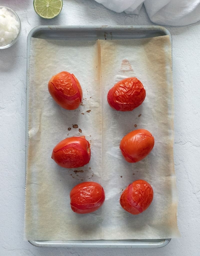 6 roma tomatoes on a baking sheet. 