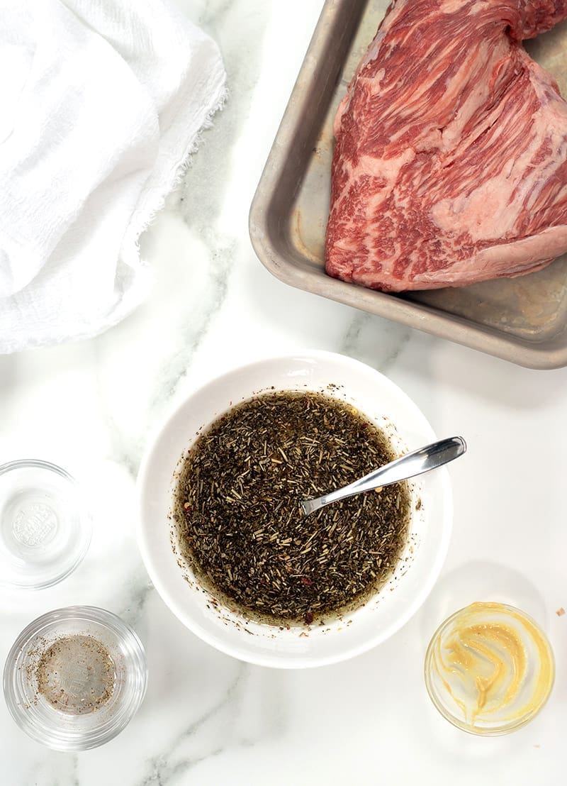 White bowl with tri tip marinade next to a raw roast.