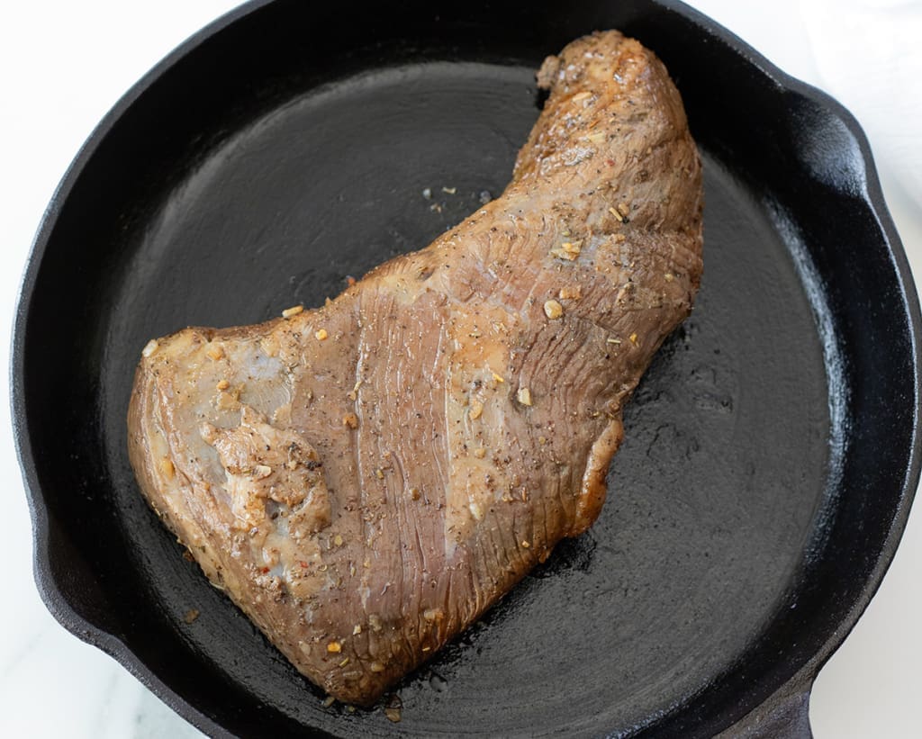 Uncooked beef roast on a black cast iron skillet.