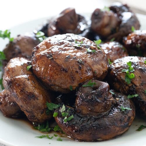 Red wine mushrooms on a white plate with parsley.