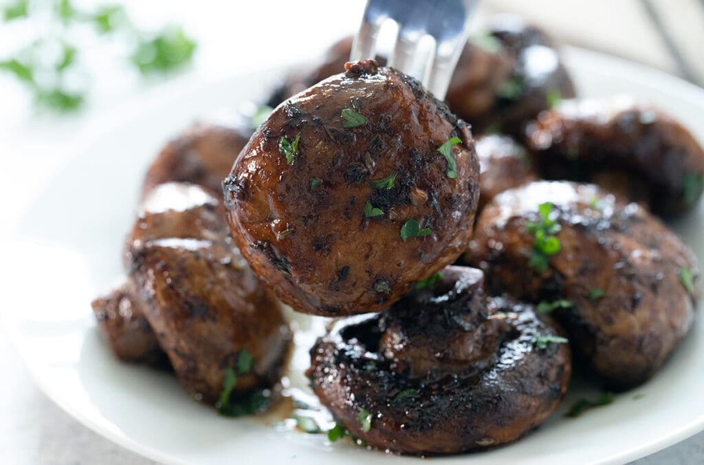 Plate of mushrooms with a fork holding one up.