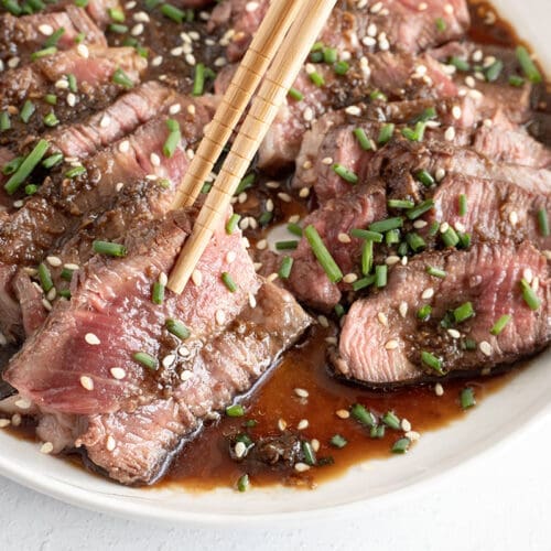 Chopsticks picking up a piece of seared steak.