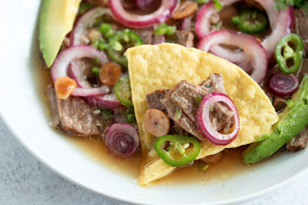 Beef aguachile on a tortilla chips.