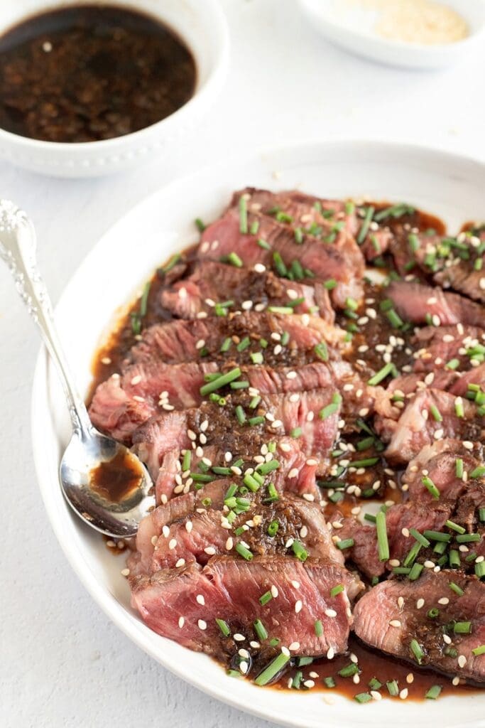 Plate of beef tataki with a silver spoon on the side.
