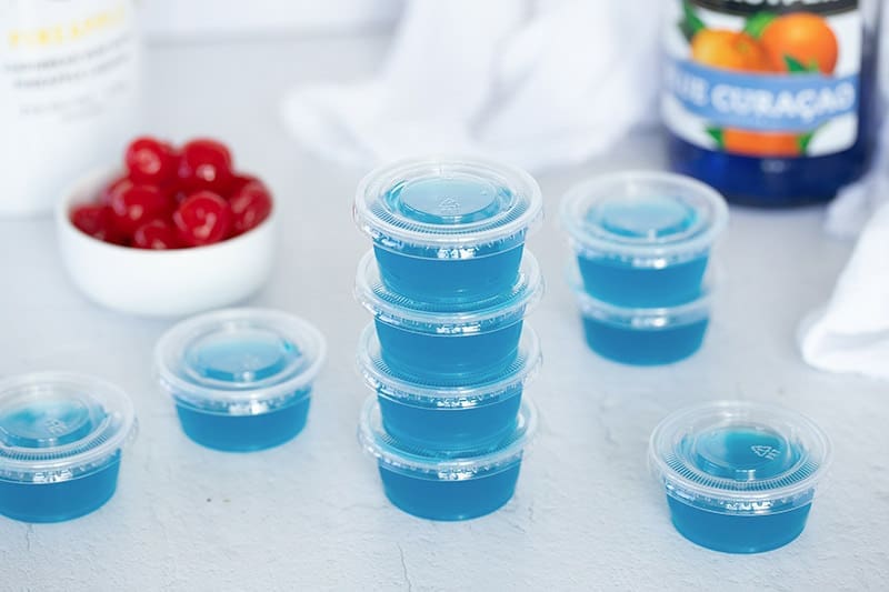 4 stacked blue raspberry jello shots.