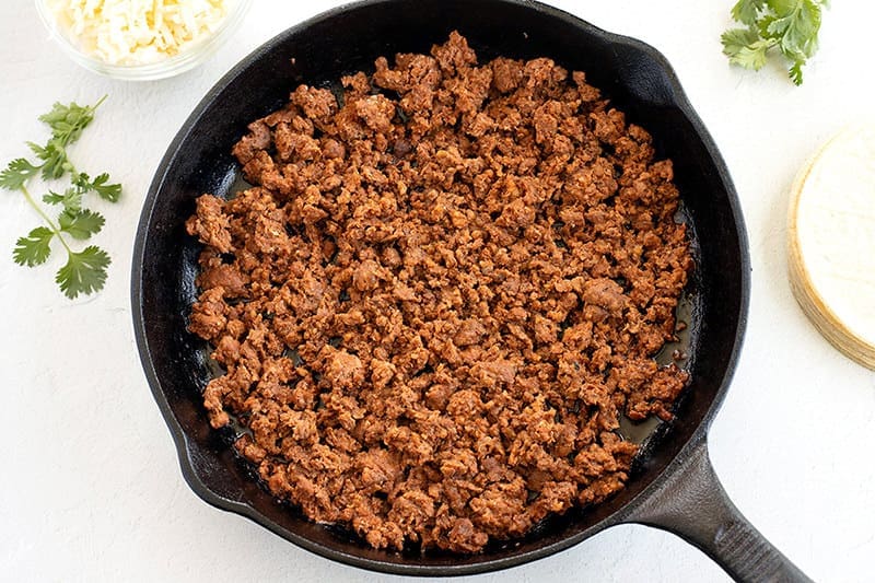 Cooked chorizo for Choriqueso in a cast iron skillet.