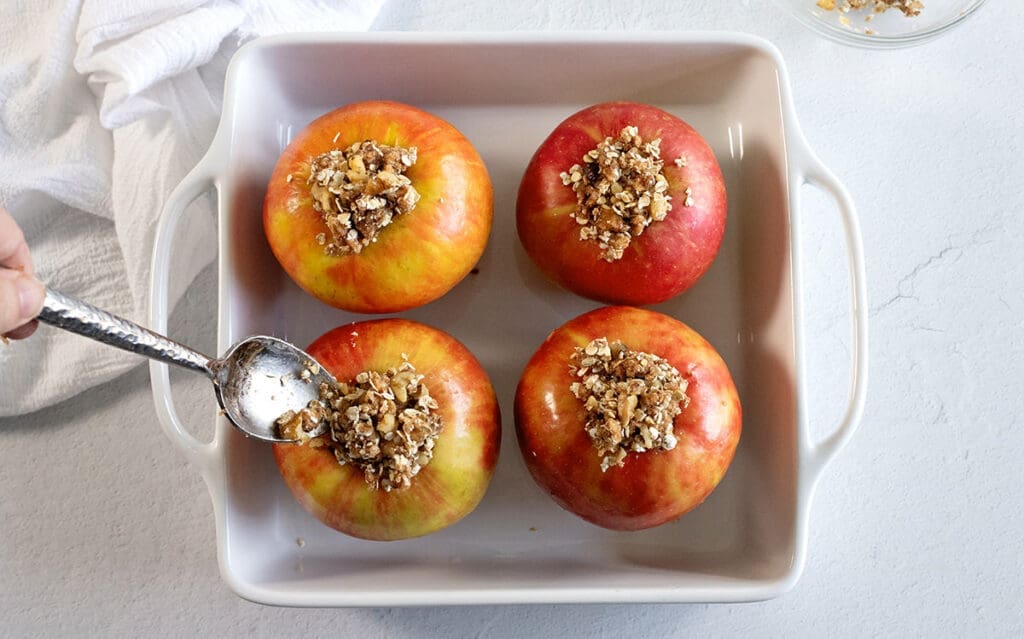 Small spoon stuffing red honeycrisps in a baking dish.