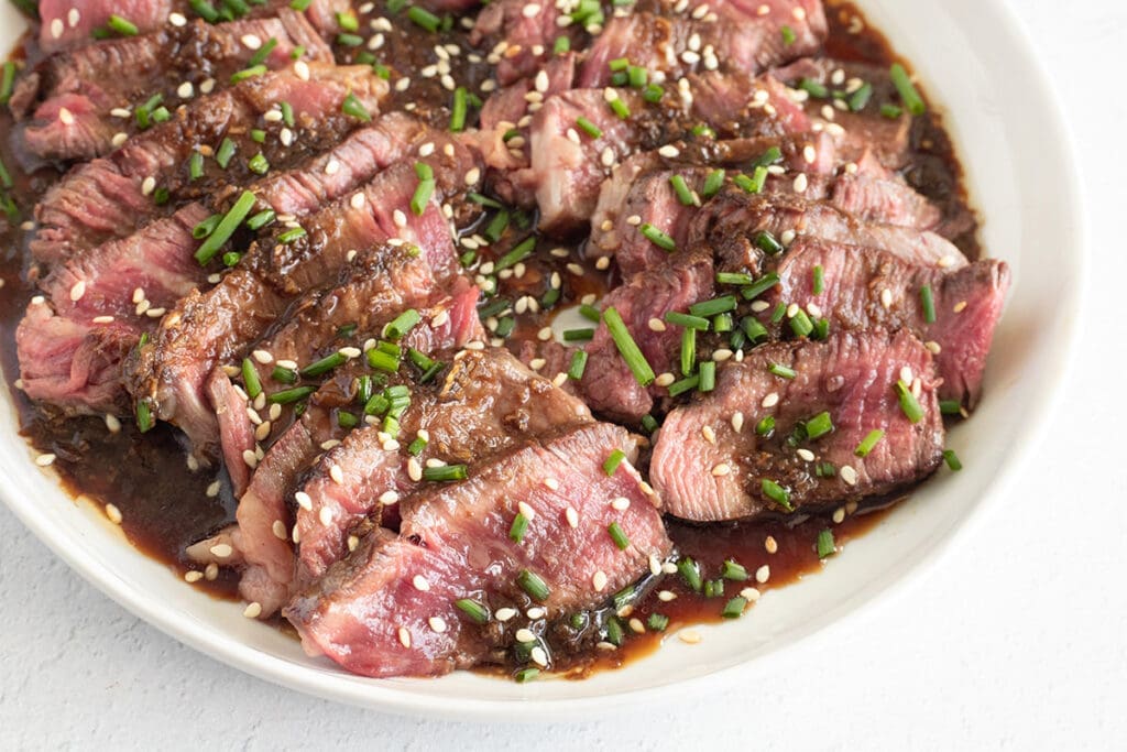 Plate of sliced steak with ponzu sauce.