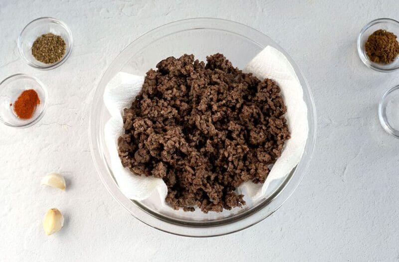 Cooked ground beef in a glass bowl.