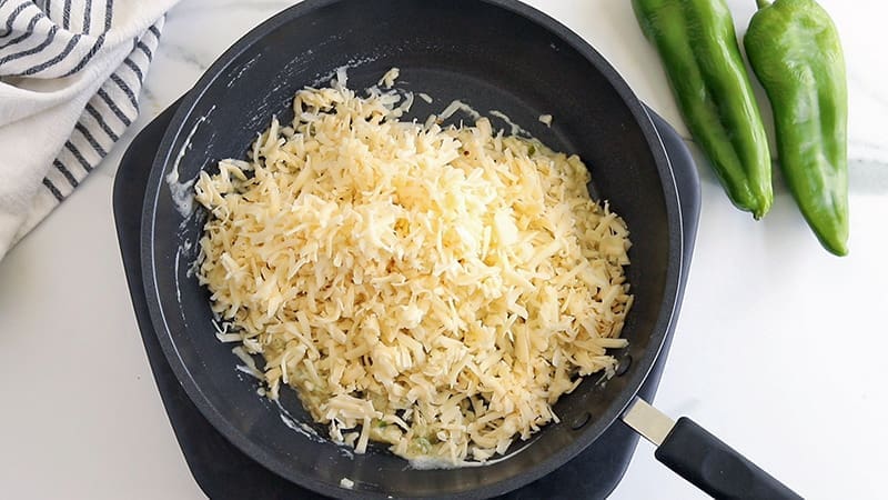 Shredded cheese in a black non stick skillet.